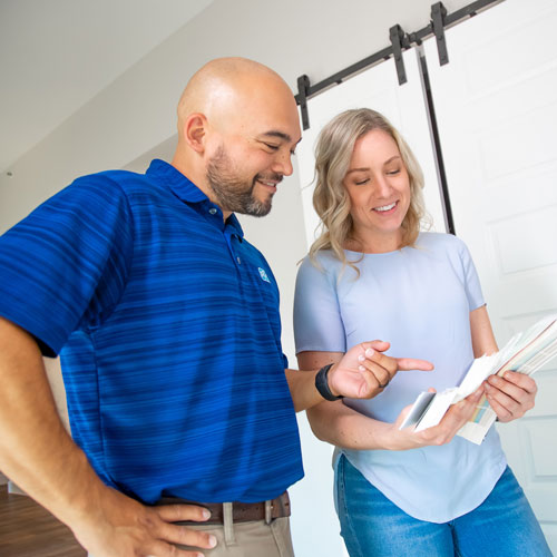 Man with dark blue shirt smiling and pointing at color swatches with smiling woman with light blue shirt