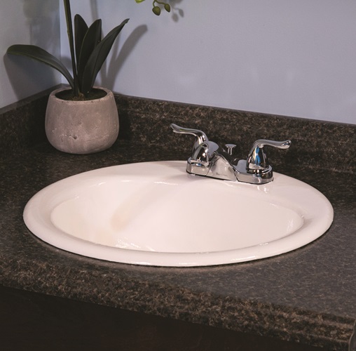 White ceramic sink with silver handles and faucet in brown counter with potted plant on top with gray wall