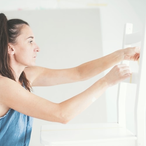 Woman with dark hair and blue top holding transparent piece in white walled room