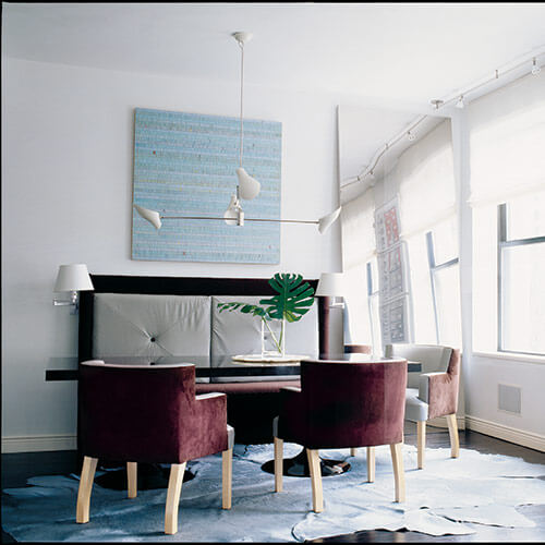 White and burgundy room with couch, table, chairs, painting, mirror and large window on right