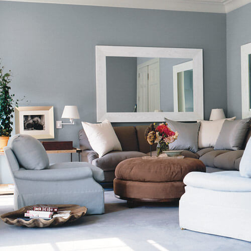 Gray and light brown livingroom with white accents with couches, chairs, and large mirrors