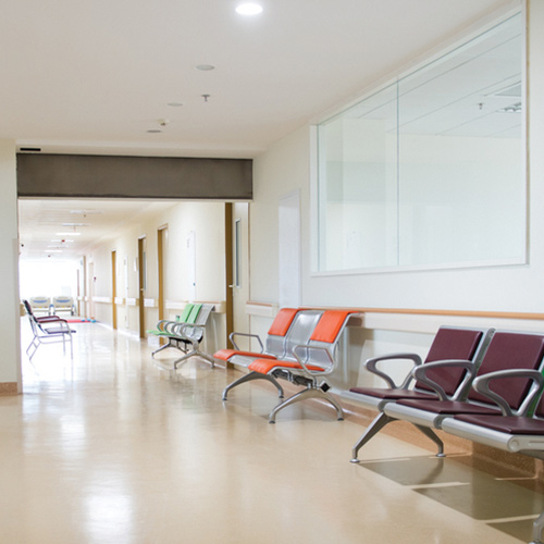 Eggshell colored hallway with green, orange, and purple groups of chairs on sides and large window and doors on walls