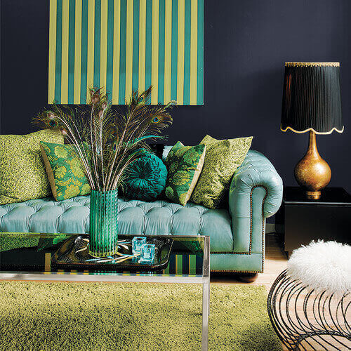 Livingroom with black wall, lamp and side table with all green shades of furniture, carpet, and painting